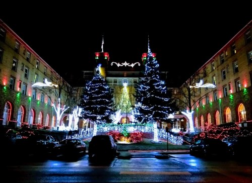 A beautifully lit building at night, featuring two large Christmas trees and colorful holiday lights.