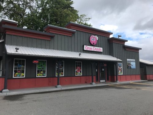Exterior of a donut shop named "Grosse Donuts," featuring a pink sign and colorful window displays.