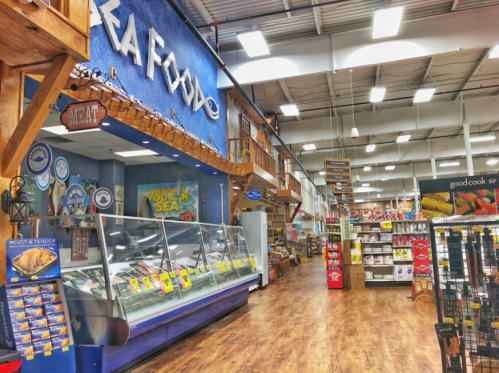 Interior of a grocery store featuring a seafood section, wooden decor, and colorful product displays.