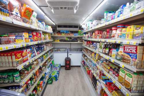 A well-stocked convenience store aisle with shelves of various packaged foods and drinks.