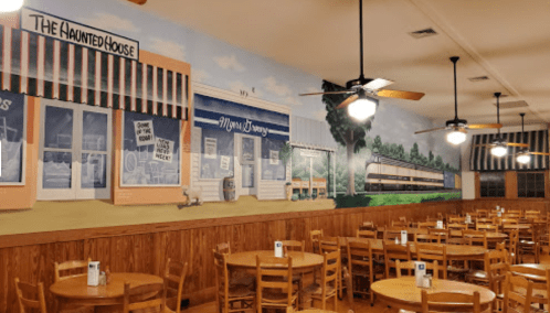 A cozy dining area with wooden tables and a mural depicting storefronts and a train on the wall.
