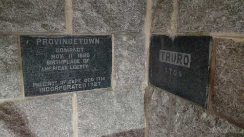 Plaques on a stone wall marking the historical sites of Provincetown and Truro, Massachusetts.