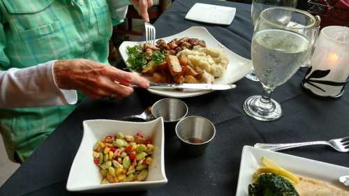 A person is dining at a restaurant, enjoying a plate of food with vegetables, mashed potatoes, and a side dish.