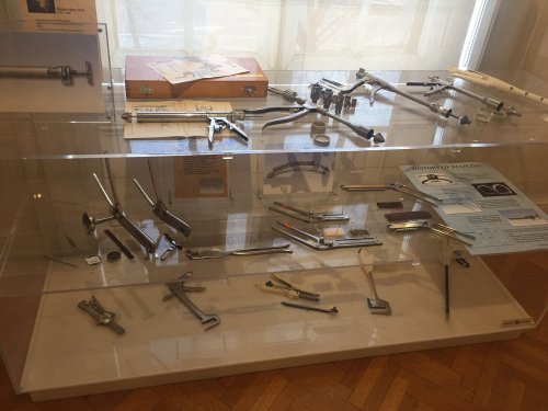 A display case featuring various metal tools and instruments, including calipers and measuring devices, in a museum setting.