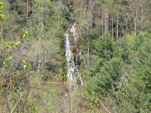 A serene waterfall cascading down rocky terrain, surrounded by lush green trees and foliage.