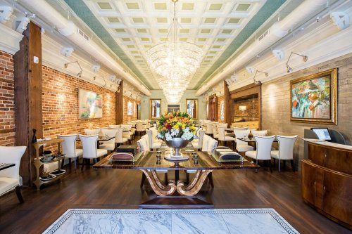 Elegant restaurant interior featuring chandeliers, brick walls, and stylish seating arrangements with floral centerpiece.
