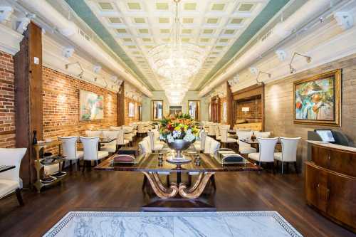 Elegant restaurant interior featuring chandeliers, brick walls, and stylish seating arrangements with floral centerpiece.