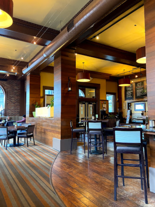 Interior of a cozy restaurant featuring wooden decor, tables, and a bar area with warm lighting.