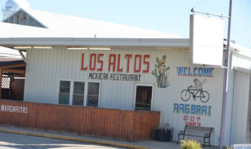 Exterior of Los Altos Mexican Restaurant with a sign welcoming RAGBRAI cyclists. Bright colors and a casual atmosphere.