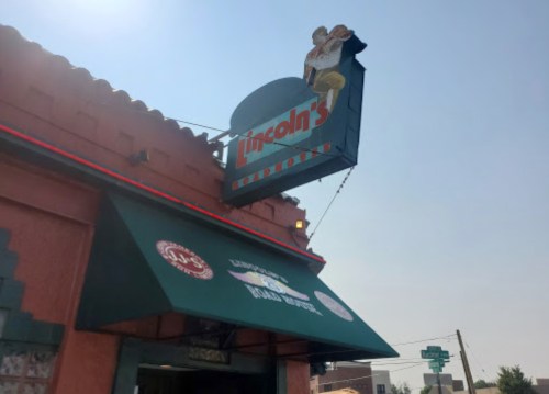 Sign for Lincoln's Restaurant with a colorful awning and clear blue sky in the background.