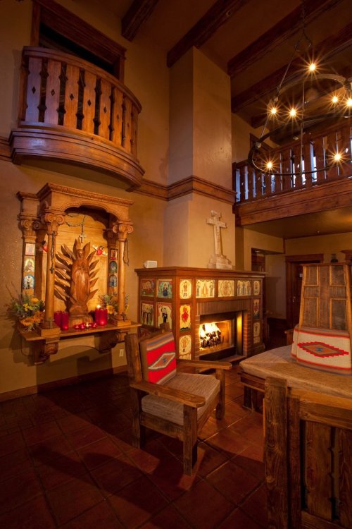 Cozy interior featuring a wooden fireplace, colorful decor, and a balcony with rustic furniture and warm lighting.