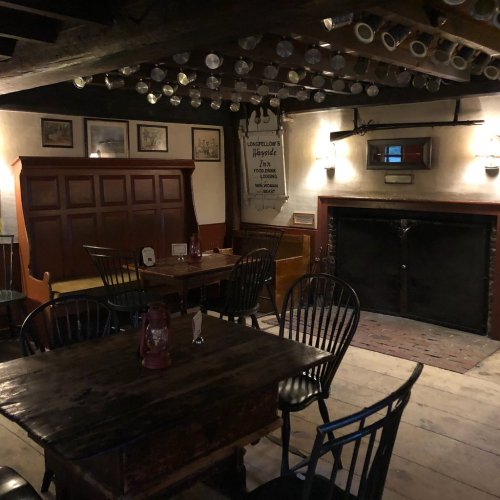 Cozy interior of a rustic pub with wooden tables, chairs, and a fireplace, adorned with vintage decor.