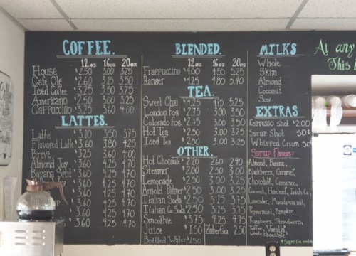 Menu board featuring coffee, blended drinks, tea, and extras with prices listed.