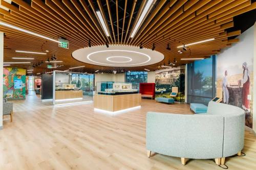 Modern office interior featuring wooden ceiling, circular lighting, and cozy seating areas. Bright and inviting atmosphere.