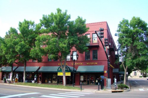 A red brick building with green awnings, labeled "Michael Gorman Museum," surrounded by trees and street signs.
