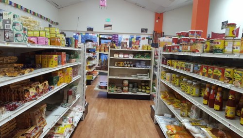 A colorful grocery store aisle filled with various packaged foods and condiments on shelves. Brightly lit and inviting.