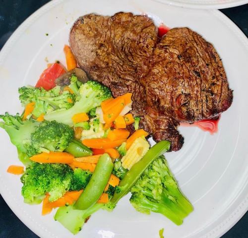 A plate with a grilled steak and a colorful mix of broccoli, carrots, and green beans.