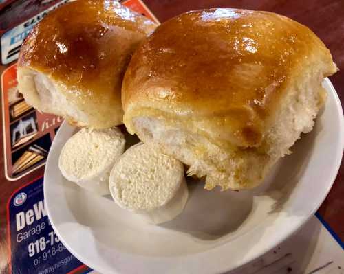 Two golden-brown bread rolls on a plate, accompanied by two small pieces of white butter.