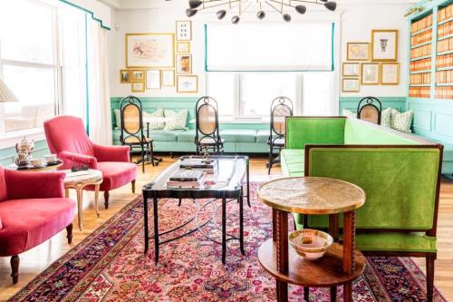 Bright living room featuring green and pink furniture, a patterned rug, and framed artwork on the walls.