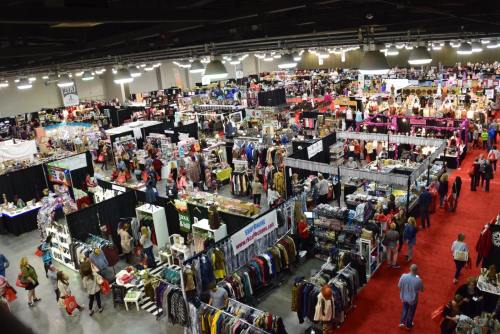 Aerial view of a bustling indoor market with numerous vendor booths and shoppers browsing various goods.