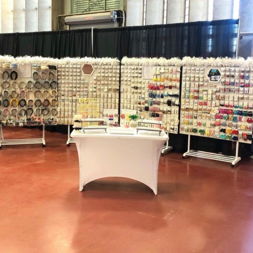 A display of colorful jewelry and accessories on stands, set up in a spacious indoor venue.
