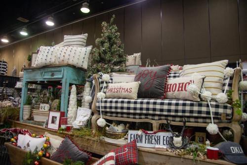 A cozy display featuring a plaid sofa with decorative pillows, a small table, and festive holiday decor.