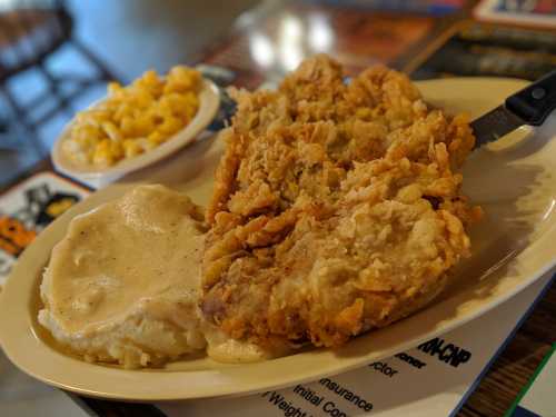 A plate of crispy fried chicken with creamy mashed potatoes and gravy, alongside a bowl of macaroni and cheese.