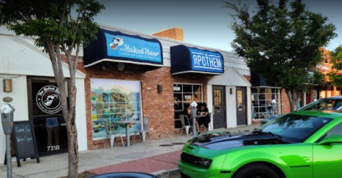 A street view of a bakery and a shop with outdoor seating, featuring a bright green car parked in front.