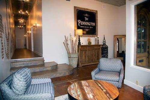 Cozy interior with two chairs, a wooden table, and decorative elements, featuring a sign that reads "The Pennington."