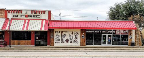 A storefront featuring two restaurants, one with red and white stripes, and the other with a wooden facade and a mural.