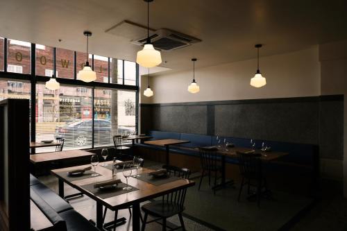 A modern restaurant interior with wooden tables, black chairs, and pendant lights, featuring large windows.