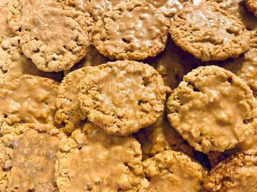 A close-up of freshly baked cookies with a golden-brown, slightly glossy surface, arranged in a pile.