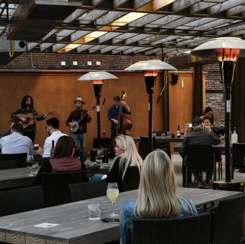 A live band performs on a patio with heaters, while guests enjoy drinks at tables.