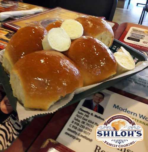 A plate of golden, fluffy rolls with butter on the side, served at Shiloh's Family Cooking.