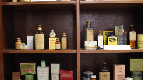 Shelves filled with vintage medicine bottles and jars, featuring various labels and packaging styles.