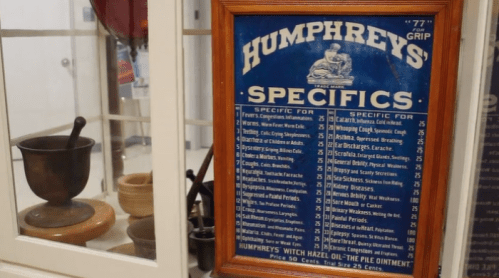 A vintage display board listing Humphrey's Specifics remedies and prices, alongside a mortar and pestle.