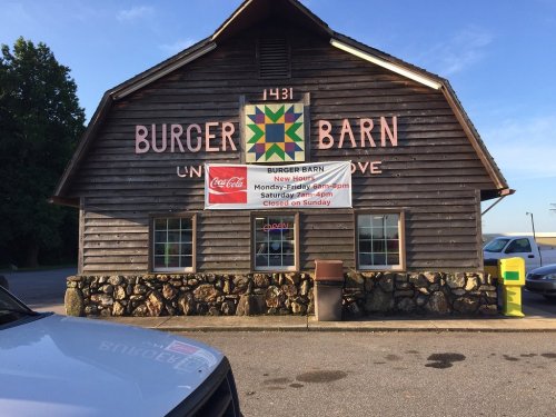 A rustic wooden building with "Burger Barn" sign, featuring a colorful quilt pattern and a Coca-Cola advertisement.