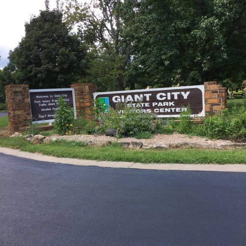 Sign for Giant City State Park, surrounded by greenery and flowers, welcoming visitors to the park.