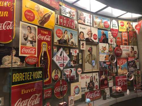 A display of vintage Coca-Cola advertisements and memorabilia in various languages and styles.