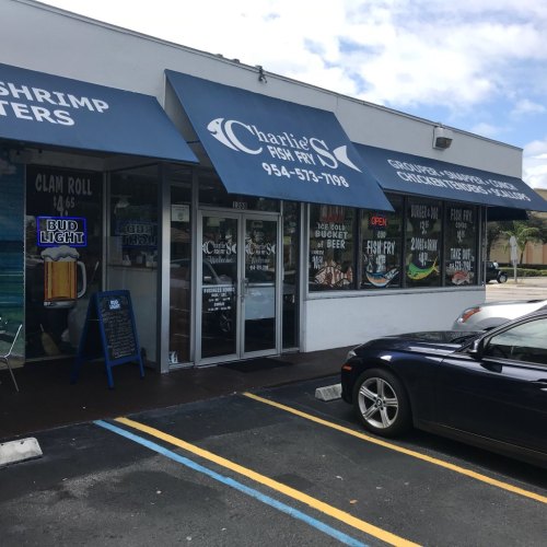 Exterior of Charlie's Seafood restaurant featuring a sign, large windows, and a parked car in front.