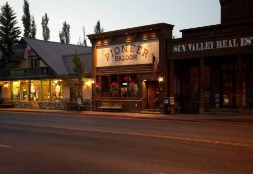 A quaint street scene featuring the Pioneer Saloon and nearby shops, illuminated in the evening light.