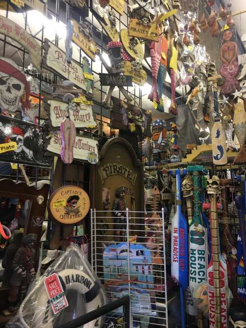 A colorful display of various decorative signs and pirate-themed items hanging in a shop.