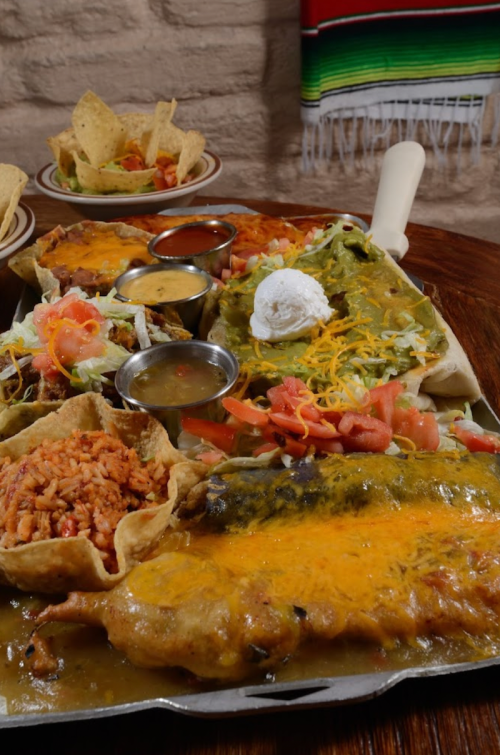 A colorful platter of enchiladas, rice, and toppings, served with chips and salsa in a festive setting.