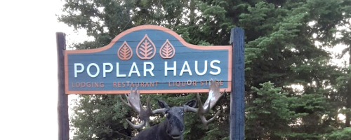 Sign for Poplar Haus featuring a moose statue, indicating lodging, restaurant, and liquor store services.