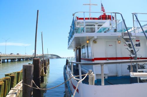 A boat docked at a pier with a bridge in the background under a clear blue sky.
