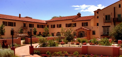 A charming adobe-style building with a landscaped garden and blue sky in the background.