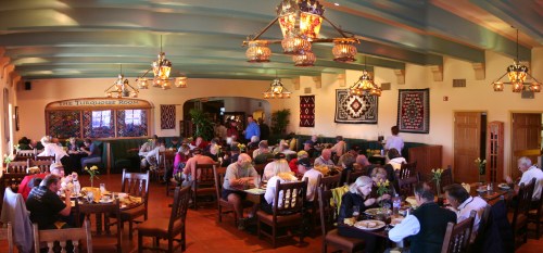 A bustling restaurant interior with diners enjoying meals, colorful decor, and unique lighting fixtures.