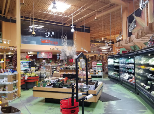 Interior of a grocery store with colorful produce displays, shelves of products, and a large refrigerated section.