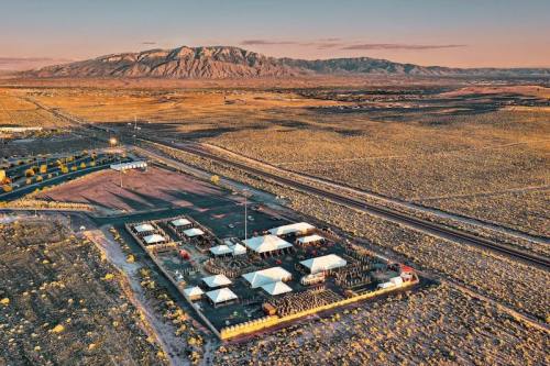 Aerial view of a desert landscape with a small event area and mountains in the background during sunset.