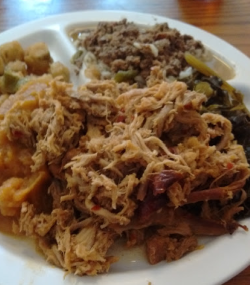 A plate of food featuring shredded meat, collard greens, okra, and a side of seasoned rice.